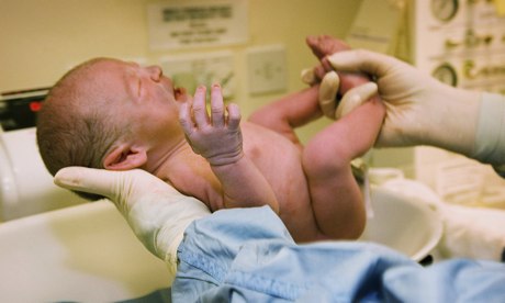 Midwife weighs newborn