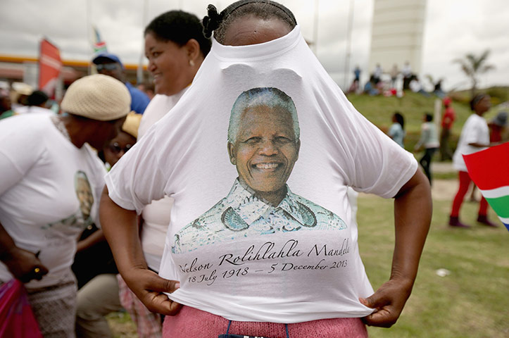 Mandela: A woman puts on her free t-shirt while waiting for the funeral cortege in M