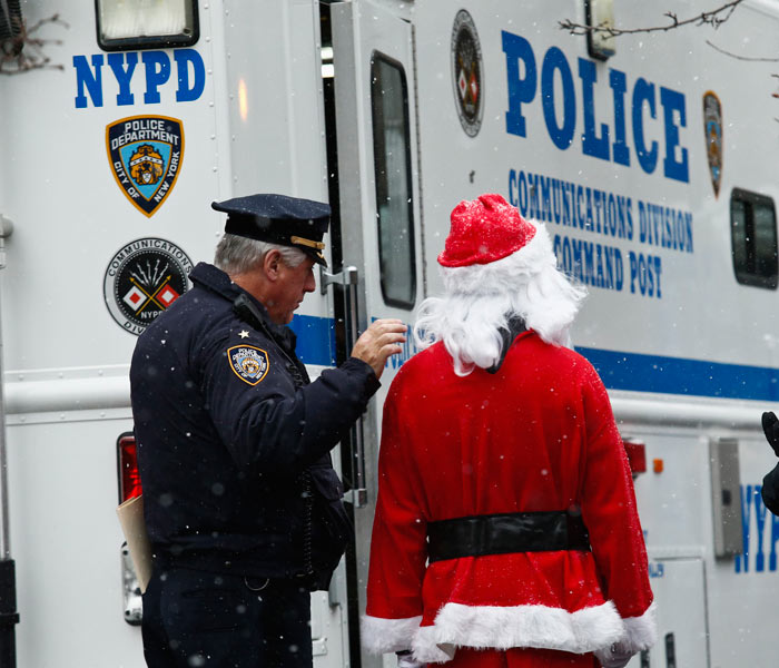 An NYPD police officer speaks with a reveller dressed as Santa Claus during the SantaCon