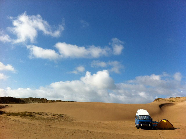 VW camper vans: blue VW camper van parked in the sand