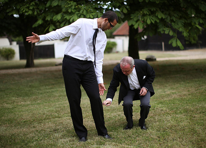Butler training school: George Telford cleans trainee butler Dwayne Cross's trousers before a party