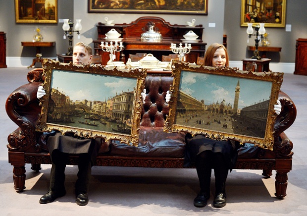 Employees of Sotheby's Auctioneers peep over paintings by Italian artist Canaletto, of the Piazza San Marco, right, and the Rialto Bridge and Grand Canal in Venice, which are being offered as a pair for sale at between £8-12m later this week, at their showroom in central London.