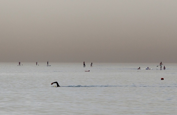 A tranquil scene of the Mediterranean sea off the shore of Tel Aviv in Israel, where the distant paddle boarders almost seem to walk on water.
