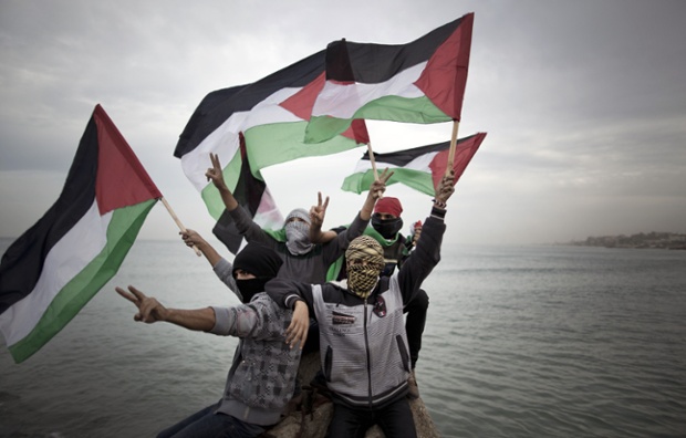In contrast, Palestinians wave a national flag before a convoy of boats is launched at the initiative of the Intifada Youth Coalition (IYC) to break the naval blockade of Gaza as a protest against the Israeli siege at the port in Gaza city.