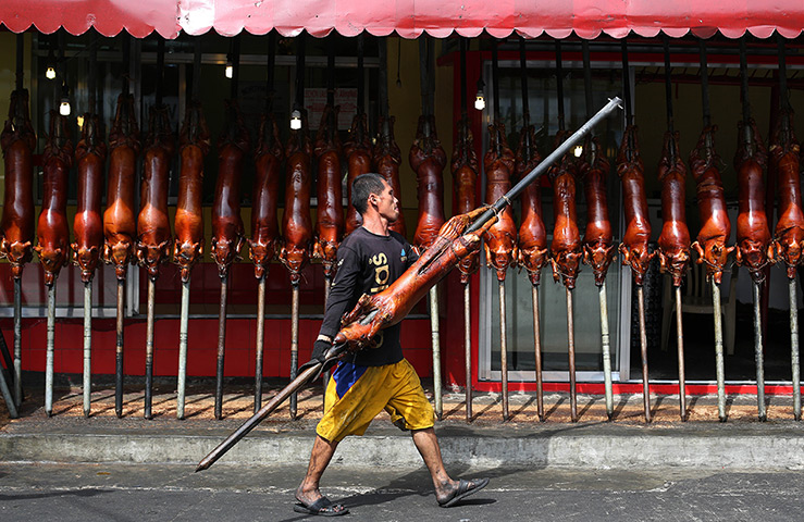 Top ten: Manila, Philippines: A worker carries roasted pig outside a store
