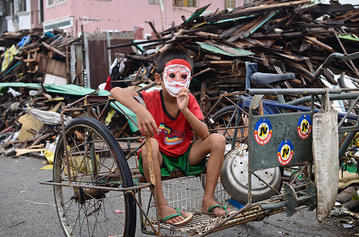 Top ten: Tacloban, Philippines: A boy with a Santa Claus mask sits on a pedicab amon