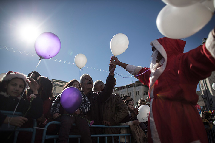 Top ten: Bethlehem, West Bank: A Palestinian man dressed as Santa Claus hands out ba