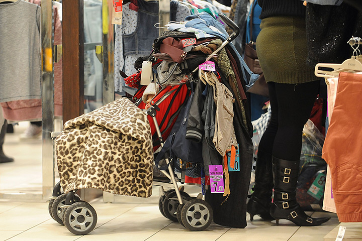 Boxing day sales: A baby is engulfed in clothes as he sleeps in his pushchair at the Highcros