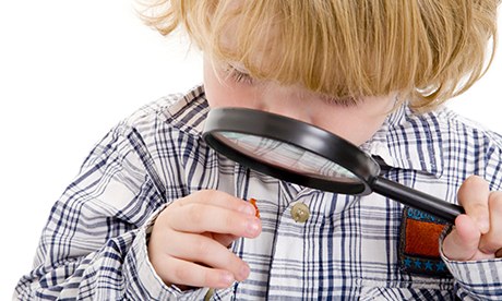 Three-year-old boy looking at a gummy bear through a magnifying glass