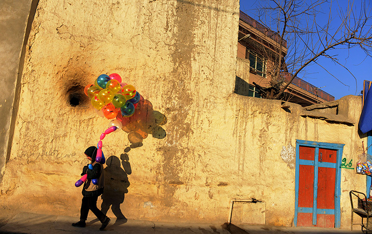 Photo highlights : Bashir, an Afghan boy who says he is five years old, holds balloons he sell