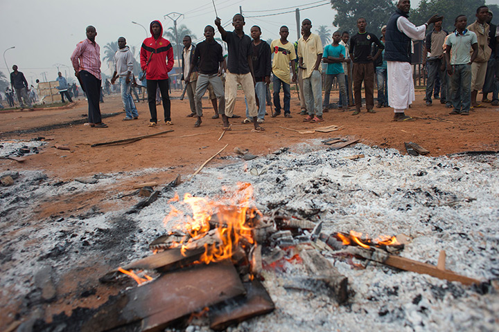 Photo highlights: Muslim residents stand behind the remains of burning furniture, as they sho