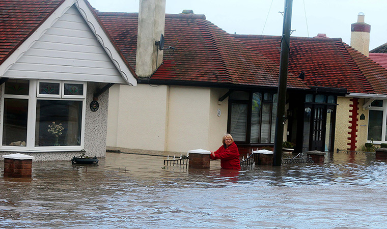UK weather: A woman stands in the flood water in Rhyl