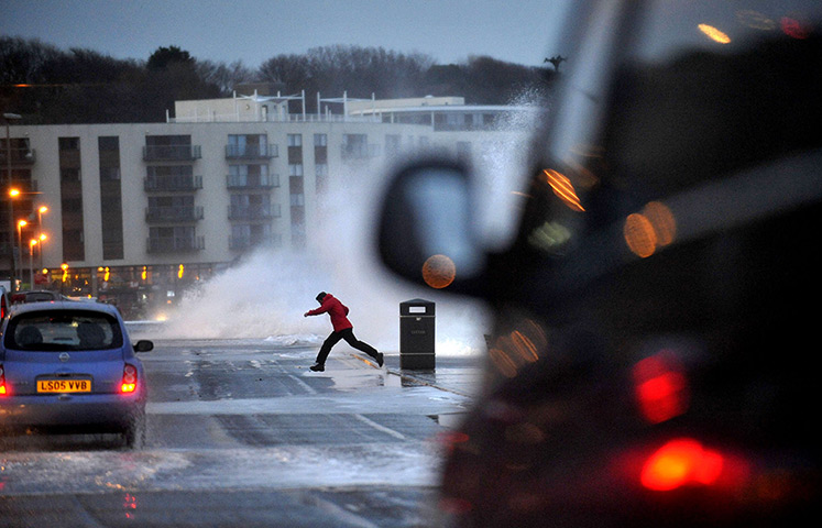 Weather UK: A person runs away from some of the large waves on Scarborough's North Bay