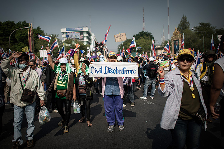 Thailand protests: Demonstrators hold a sign as they march towards government buildings
