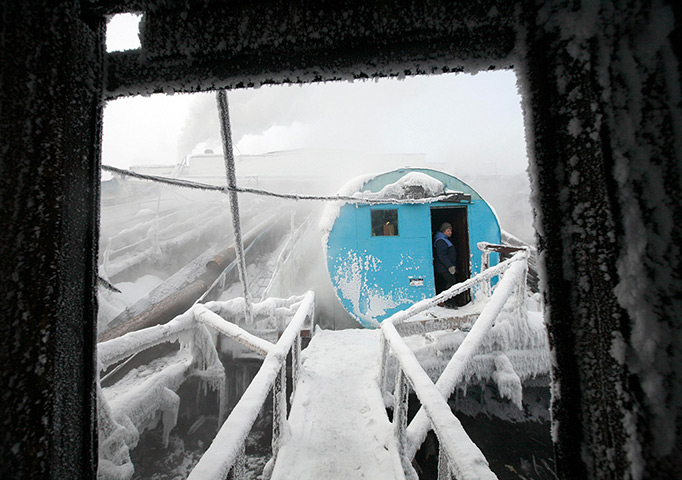 24 hours in pictures: An employee looks out from an old iron tank covered in ice