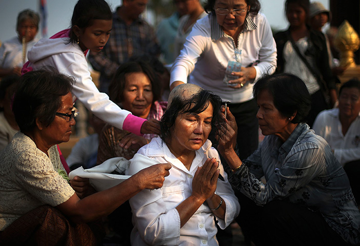 24 hours in pictures: A woman sits prayerfully while her head is shaved to mourn Cambodian King
