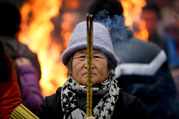24 hours in pictures: A woman burns incense in prayer China Lunar New Year
