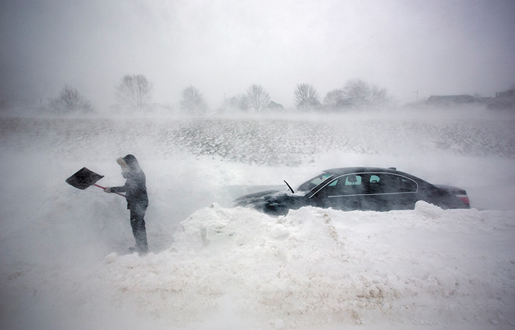 24 hours in pictures: A woman digs out her car after it was blocked in by a blizzard