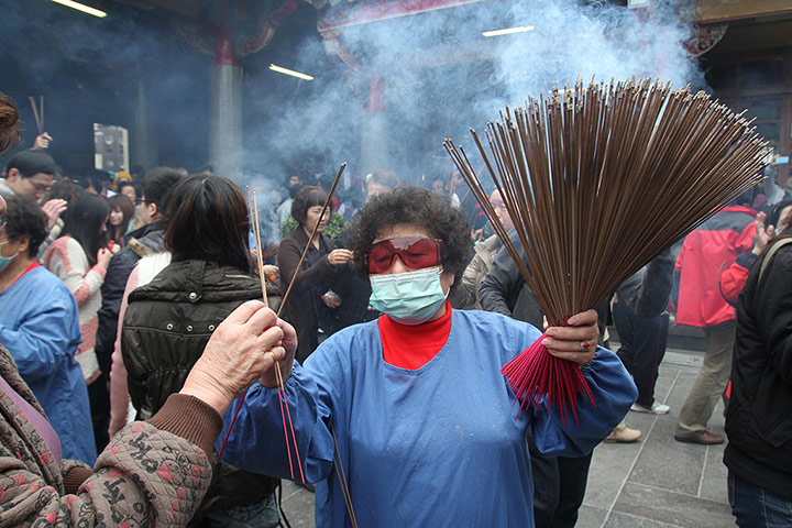 Chinese New Year: A volunteer distributes incense to temple goers