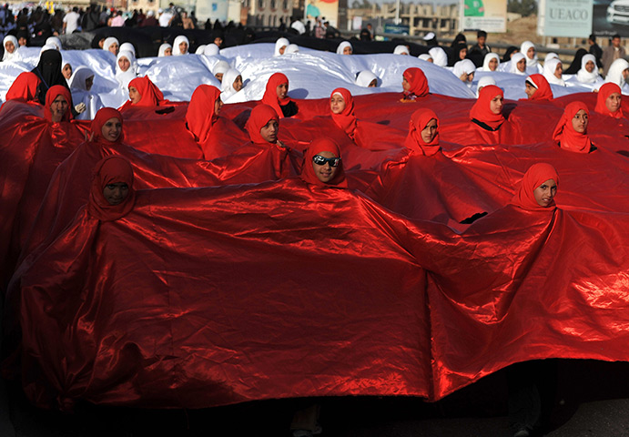 24 hours: Sana'a, Yemen: Girls appear through holes in a big Yemeni flag