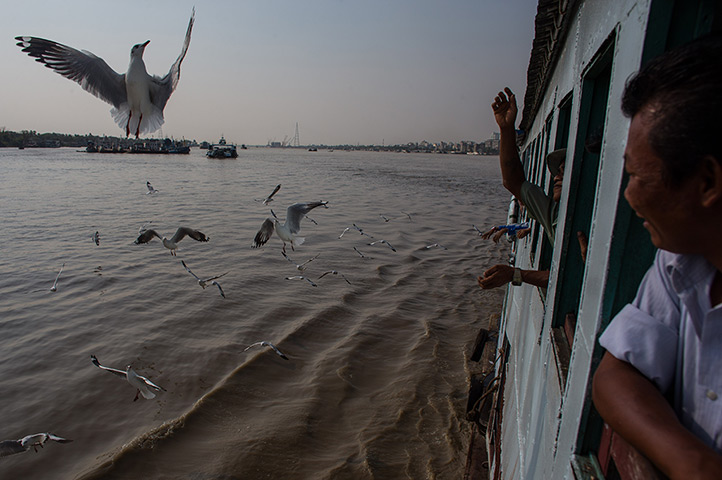 24 hours: Rangoon, Burma: A man feeds seagulls from the window of a passenger ferry 