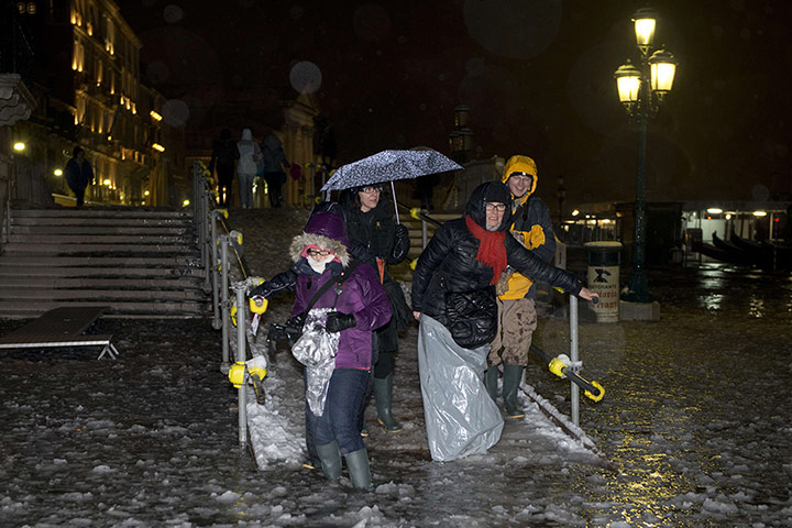 Venice in the snow: Tourist walk in the icy water during an