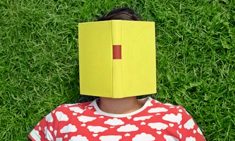 A woman lying on the grass with a book on her face