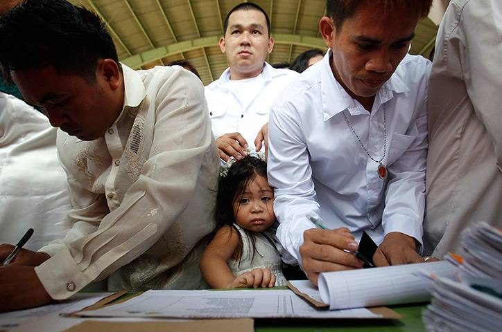 24 hours: Quezon City, Philippines: A girl is flanked by grooms 