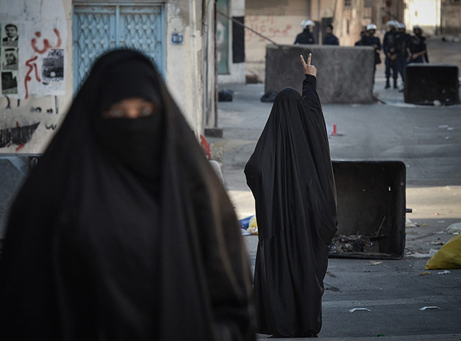 20 Photos: A Shiite Bahraini woman flashes the victory sign at security forces