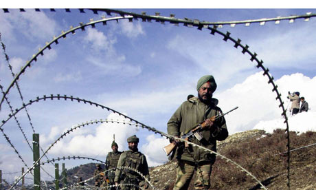 Indian soldiers patrol along a barbed-wire fence in Kashmir