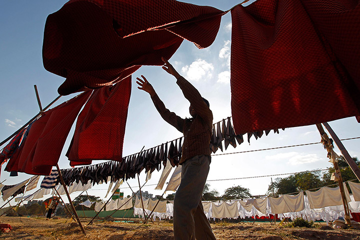 24 hours: Ahmedabad, India: A clothes washer, tries to retrieve a piece of cloth