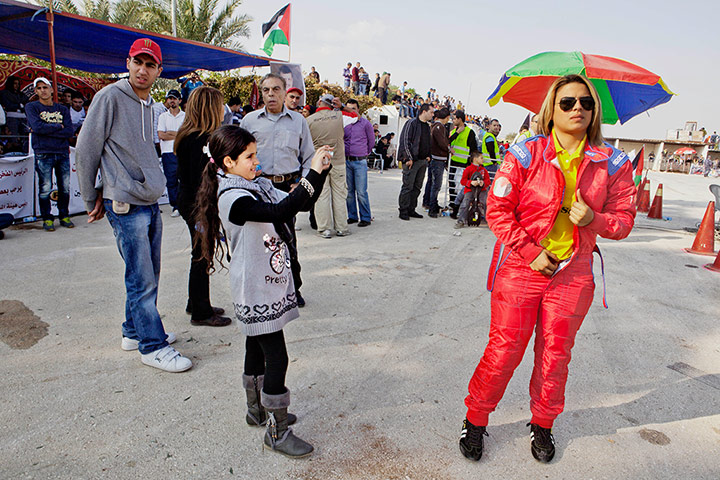Big Pic - Tanya Habjouqa: female racing driver with umbrella and child photographer