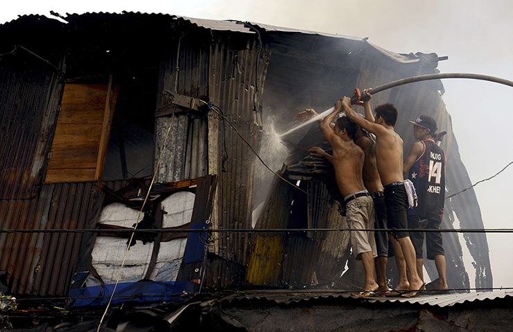 24 hours in pictures: Residents use a firemen's hose to extinguish a fire that engulfed a slum