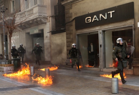 Riot police run by closed shops after protesters threw a petrol bomb following an anti-austerity march during a 24-hour strike February 20, 2013.