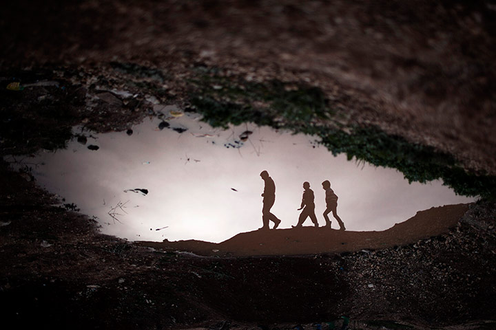20 Photos: Displaced Syrian children reflected in a puddle near the Azaz camp