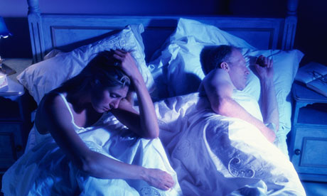 A sleepless woman next to her partner in bed