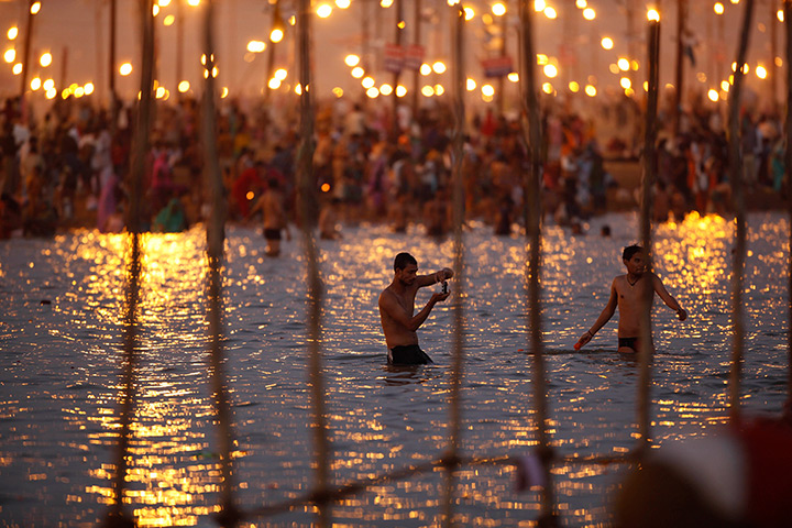 24hours in pictures: A man takes pictures as Indian Hindu devotees take dips at Sangam