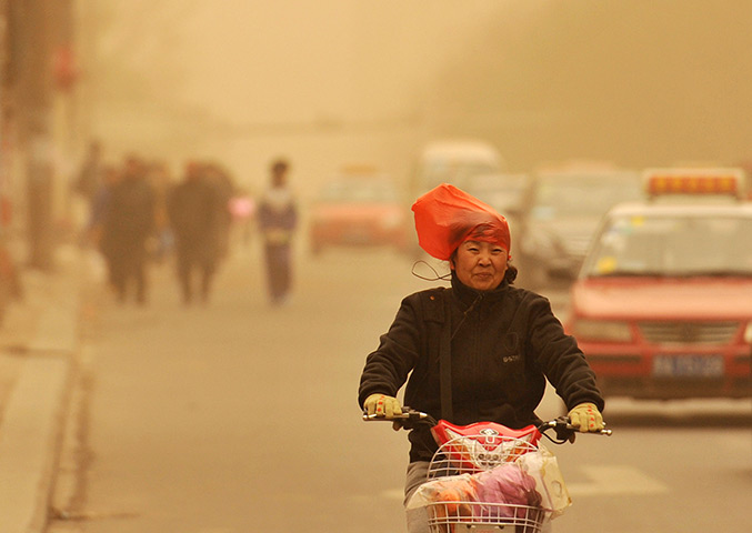 24 hours in pictures: A woman wearing a plastic bag over her head rides along a street 