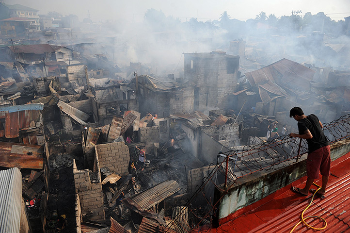 24 hours in pictures: A resident looking at destroyed houses after a fire engulfed a slum area