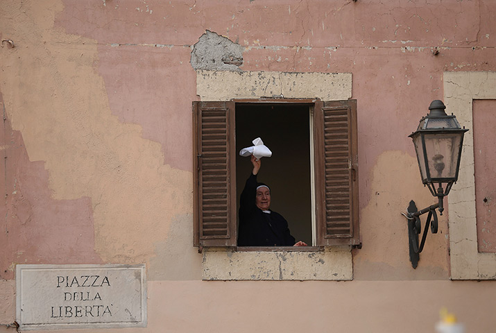 The Pope's last day: A nun waves her handkerchief as she waits for the Pope 