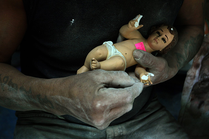 24 hours: Morelos, Mexico: A craftsman restores a figurine of a baby Jesus