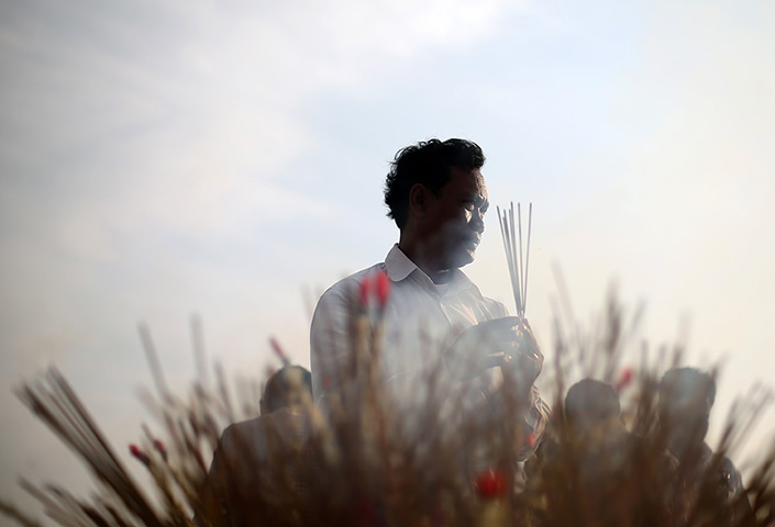 24 hours: Phnom Penh, Cambodia: A man prays with incense sticks