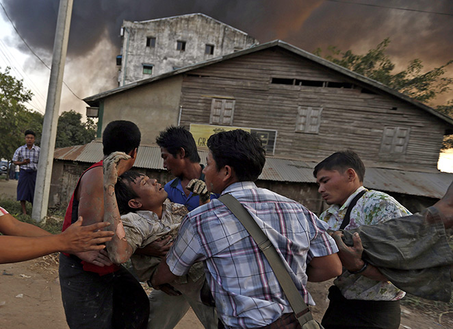 24 hours: Rangoon, Burma: People carry an injured person after a fire and explosion