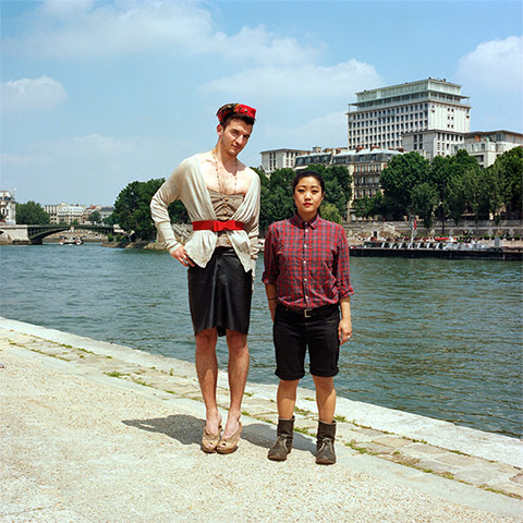 Big Picture - Hana Pesut: couple clothes swapping hana pesut switcheroo man wearing leather skirt and cream cardigan with red belt woman wearing checked shirt and black shorts