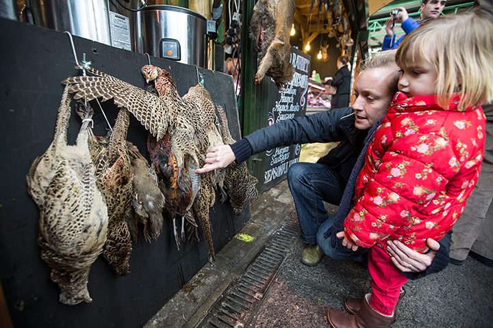 Borough Market: A woman and her child look at some pheasants hanging at a stall