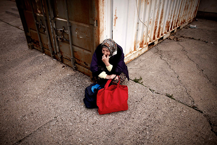 24 hours in pictures: A woman waits for food in front of a soup-kitchen Bosnia