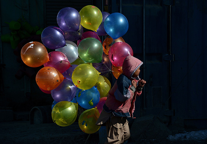 24 hours in pictures: An Afghan boy walks with balloons