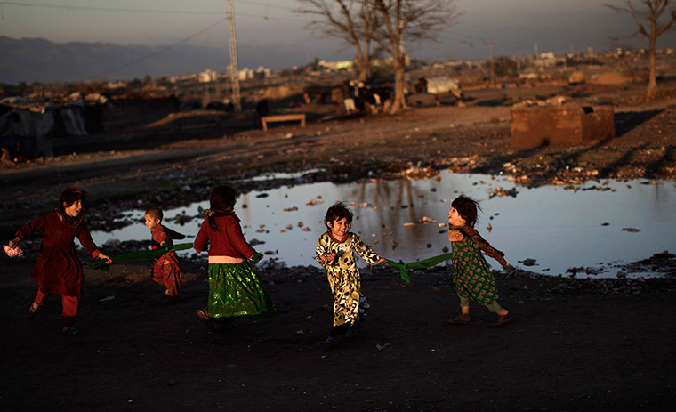 24 hours in pictures: Afghan refugee girls play next to a puddle of rain