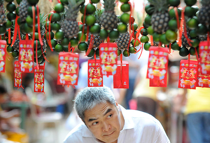 24 Hours: Manila, Philippines: A man walks beneath Chinese fruit charms in Chinatown
