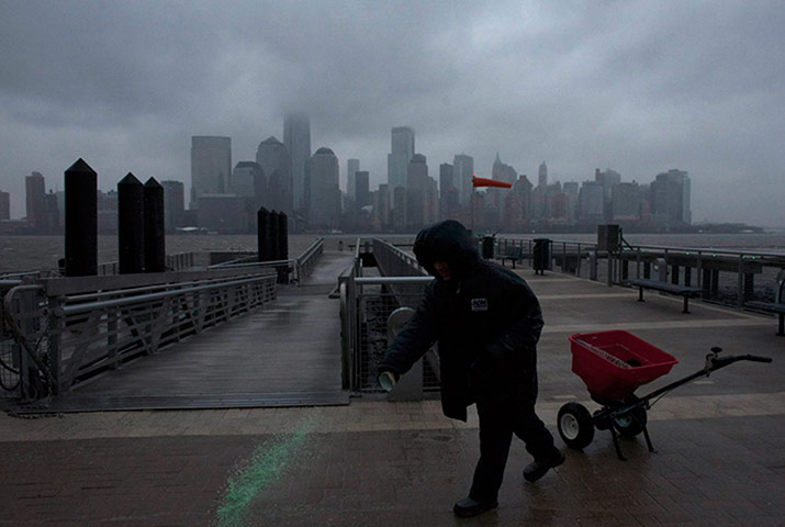 us blizzard: A man throws salt for the snow